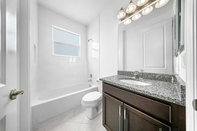a bathroom with a granite countertop sink a toilet and bathtub