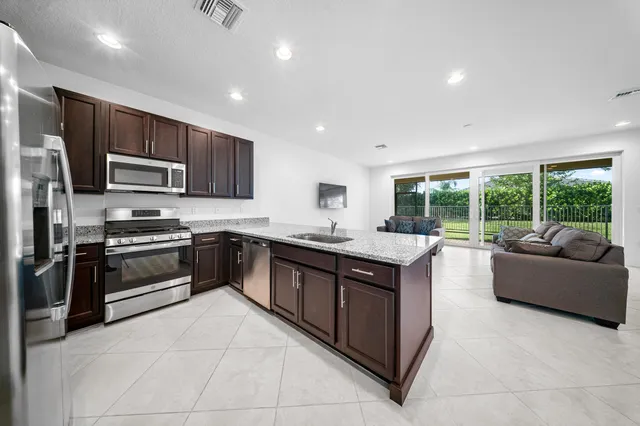 a large kitchen with stainless steel appliances granite countertop a stove and a sink