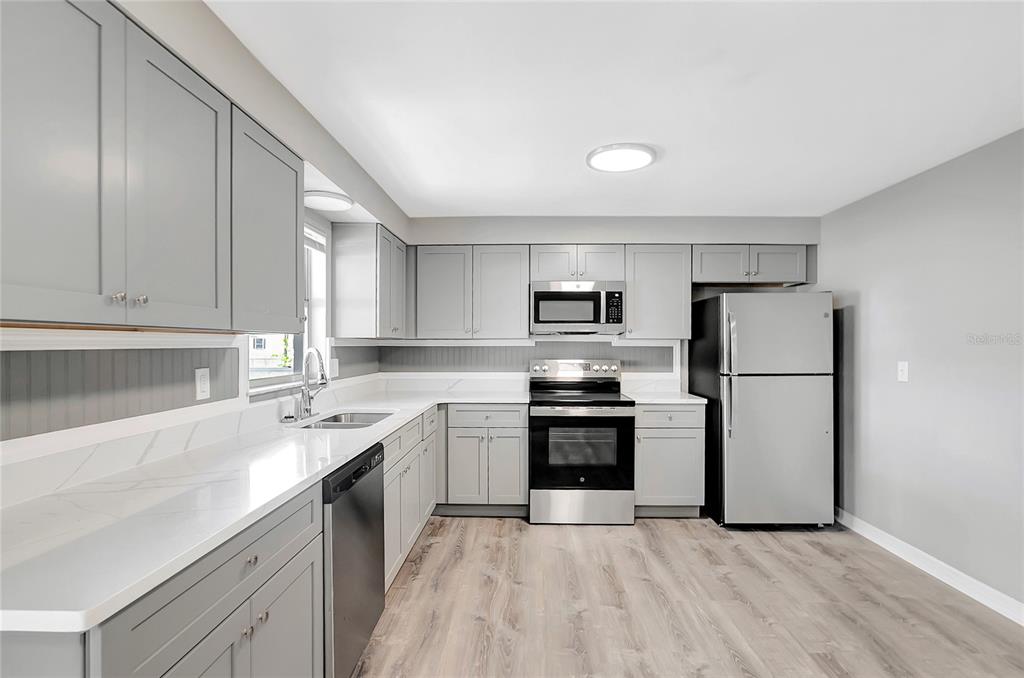 5900 Beech Street Zephyrhills, FL 33542 - Photo 13 of 37 a kitchen with a sink a refrigerator and white cabinets