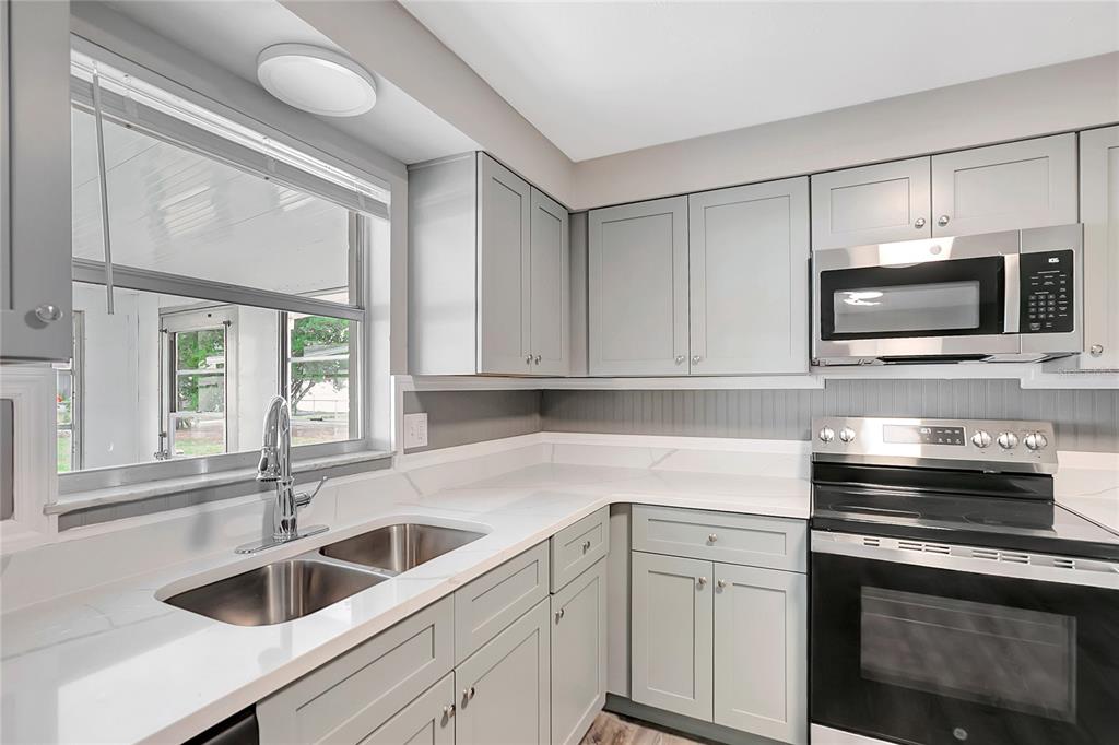 5900 Beech Street Zephyrhills, FL 33542 - Photo 14 of 37 a kitchen with granite countertop white cabinets white stainless steel appliances and a sink