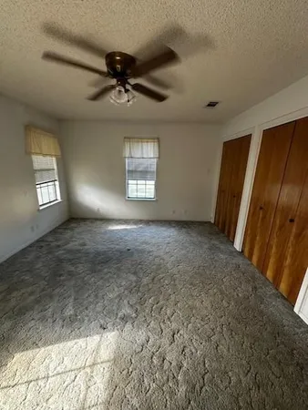 an empty room with windows and fan