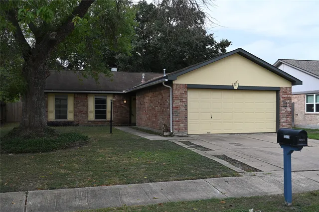 a view of a house with a yard plants and large tree
