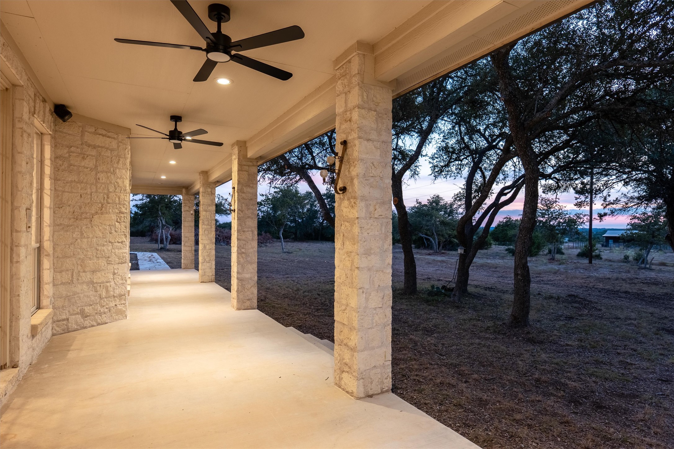 1651 Old Red Ranch Road Dripping Springs, TX 78620 - Photo 26 of 31 Stone pillars line a covered back porch overlooking mature trees and open fields.