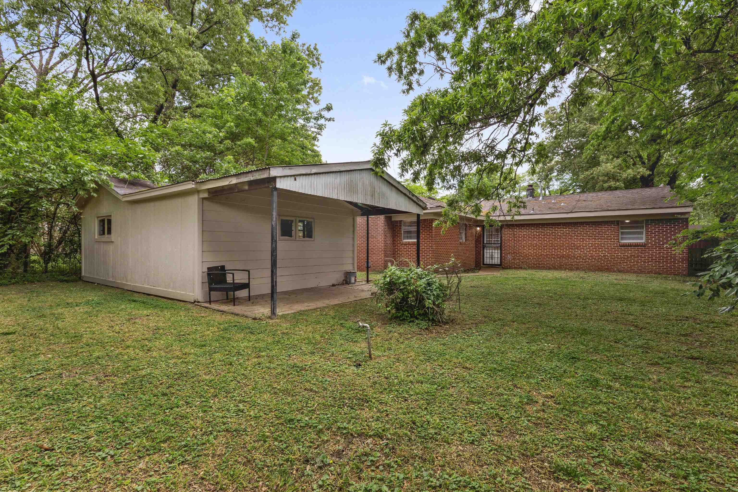 4565 Verne Road Memphis, TN 38117 - Photo 17 of 18 Spacious backyard featuring a detached outbuilding with covered patio, brick exterior home, and mature trees