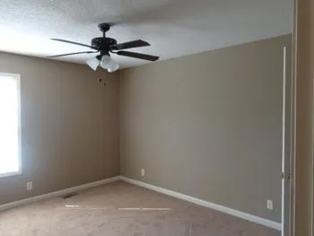 an empty room with a window and a fan