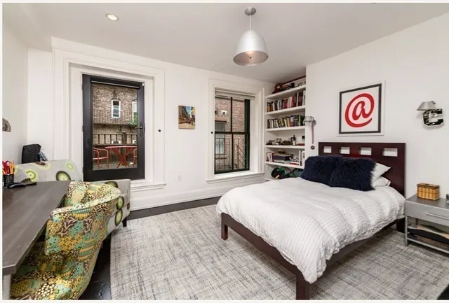 a bedroom with a bed and dresser with wooden floor