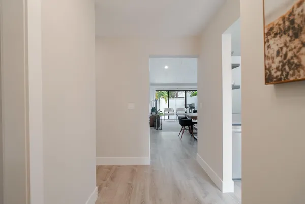 a view of a hallway with wooden floor and a livingroom with furniture
