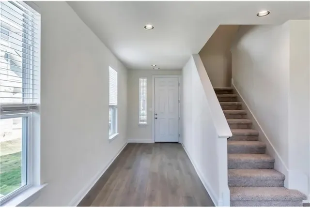 a view of a hallway with wooden floor and stairs