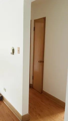 an empty room with wooden floor and windows with curtains