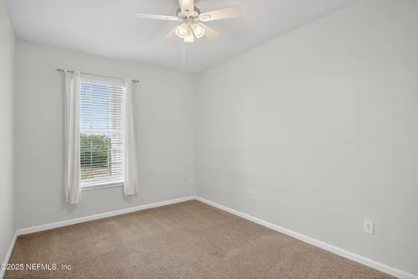 a view of an empty room with a chandelier fan