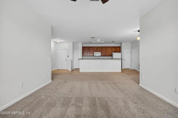 an empty room with a kitchen and a ceiling fan