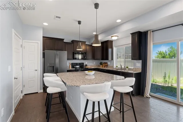 a kitchen with stainless steel appliances a dining table chairs refrigerator and sink