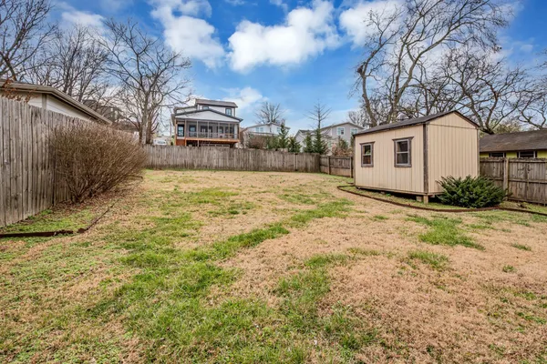 a view of a blue house with yard and a large tree