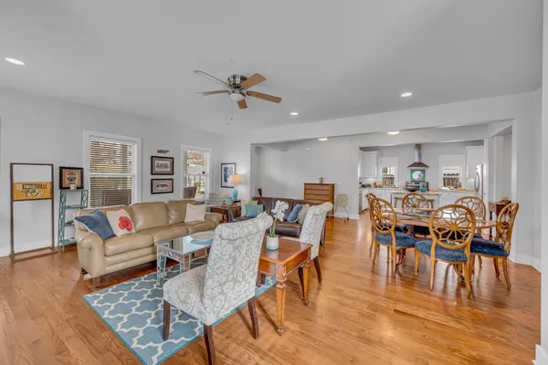 a living room with lots of furniture a wooden floor and a rug