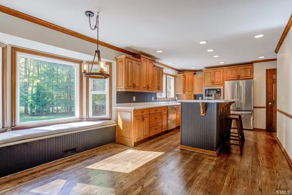 a kitchen with stainless steel appliances granite countertop a refrigerator a stove top oven and a sink with wooden floor