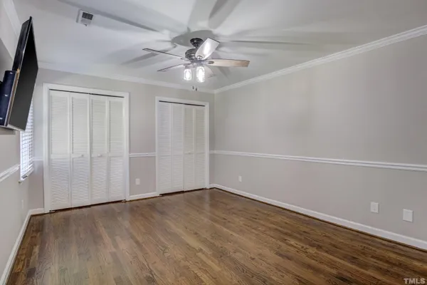 an empty room with wooden floor fan and windows