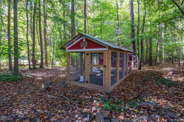 a view of a house with large trees and wooden fence