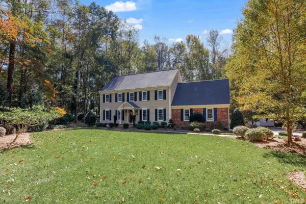 a view of a house with a big yard and large trees