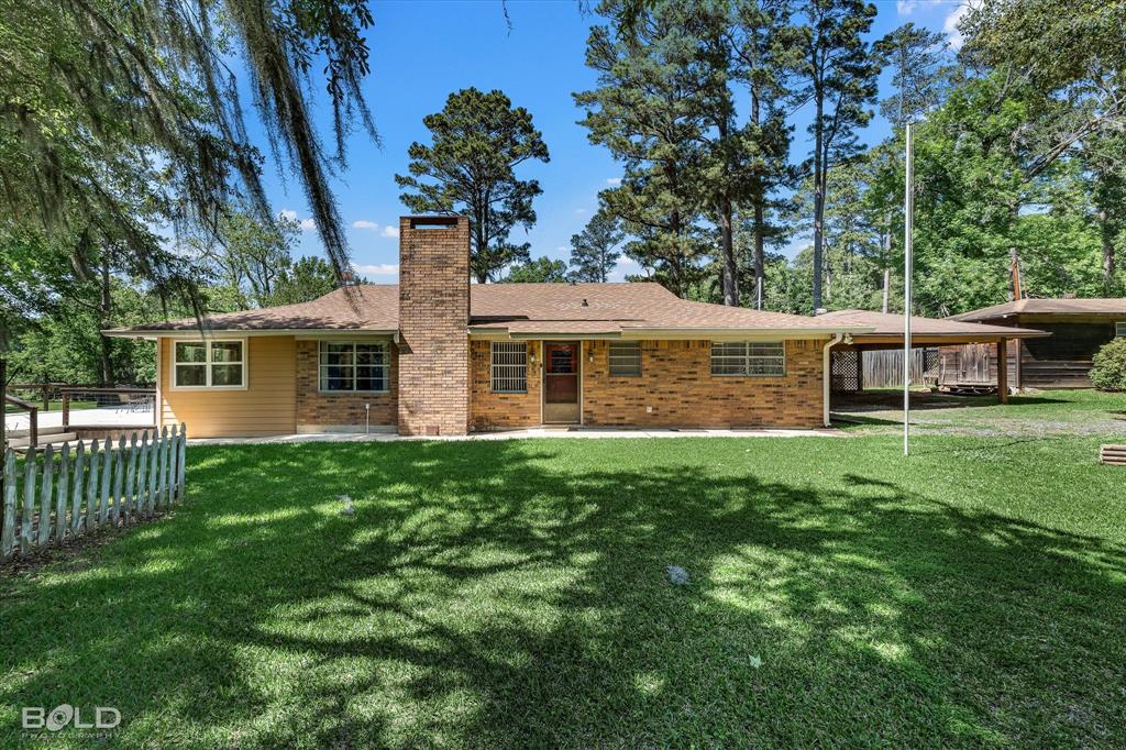 225 Marie Road Ringgold, LA 71068 - Photo 10 of 40 Brick exterior home featuring a prominent chimney, a covered carport, a light-colored shingle roof, and multiple windows