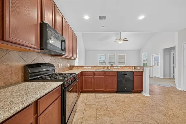 a kitchen with stainless steel appliances granite countertop a stove a sink dishwasher and a microwave oven with cabinets