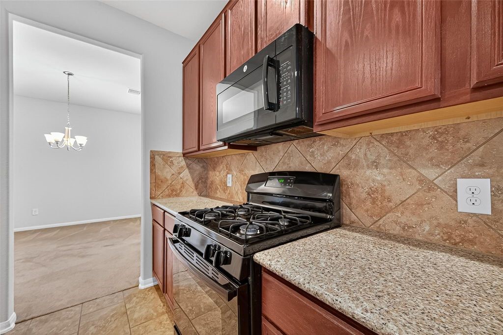 3218 Dappled Vale Trail Spring, TX 77373 - Photo 19 of 47 a kitchen with stainless steel appliances granite countertop a stove a microwave and a sink