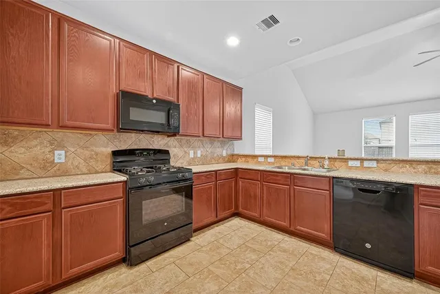 a kitchen with stainless steel appliances granite countertop wooden cabinets stove top oven and sink