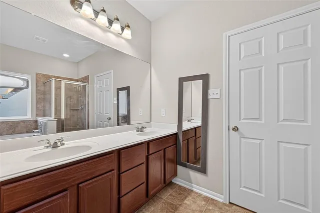 a bathroom with double vanity sinks a vanity a lamp and a mirror