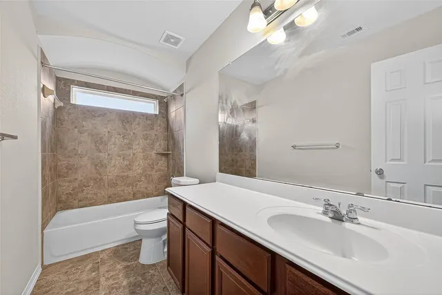 a bathroom with a bathtub shower sink vanity mirror and toilet