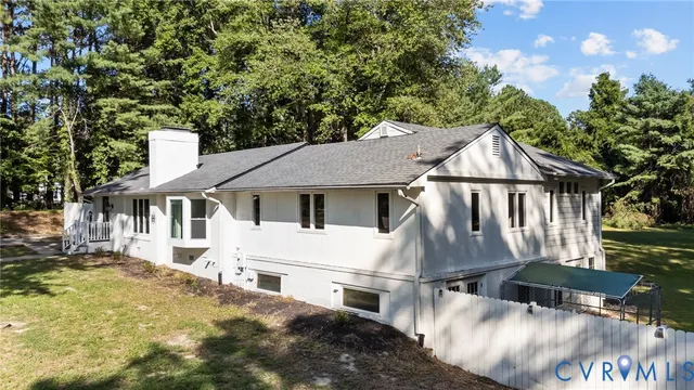 a view of a white house with a yard plants and large tree