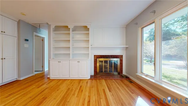 a view of empty room with wooden floor and fireplace