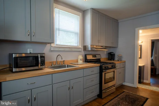 a kitchen with granite countertop white cabinets stainless steel appliances a sink and a window