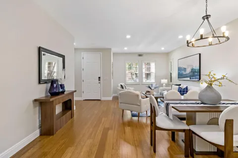 a kitchen with stainless steel appliances granite countertop a stove a sink a refrigerator a dining table and chairs with wooden floor