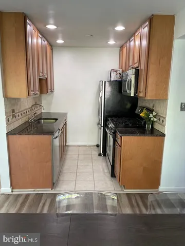 a kitchen with stainless steel appliances granite countertop a refrigerator a stove and a sink