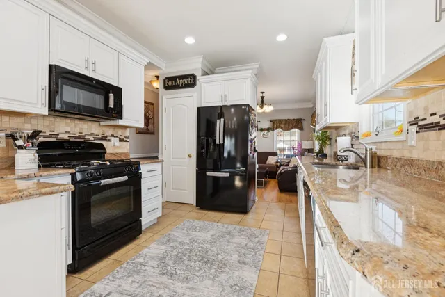 a kitchen with stainless steel appliances granite countertop a refrigerator a stove top oven a sink a dining table and chairs