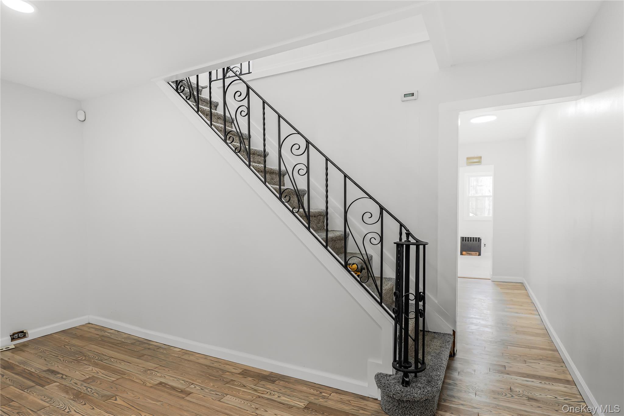 173-43 103rd Road Queens, NY 11433 - Photo 32 of 43 Hardwood-style flooring throughout, carpeted staircase, and decorative wrought iron stair railing