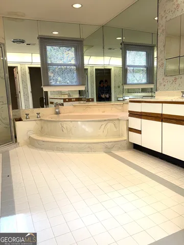 a spacious bathroom with a large tub sink shower and mirror