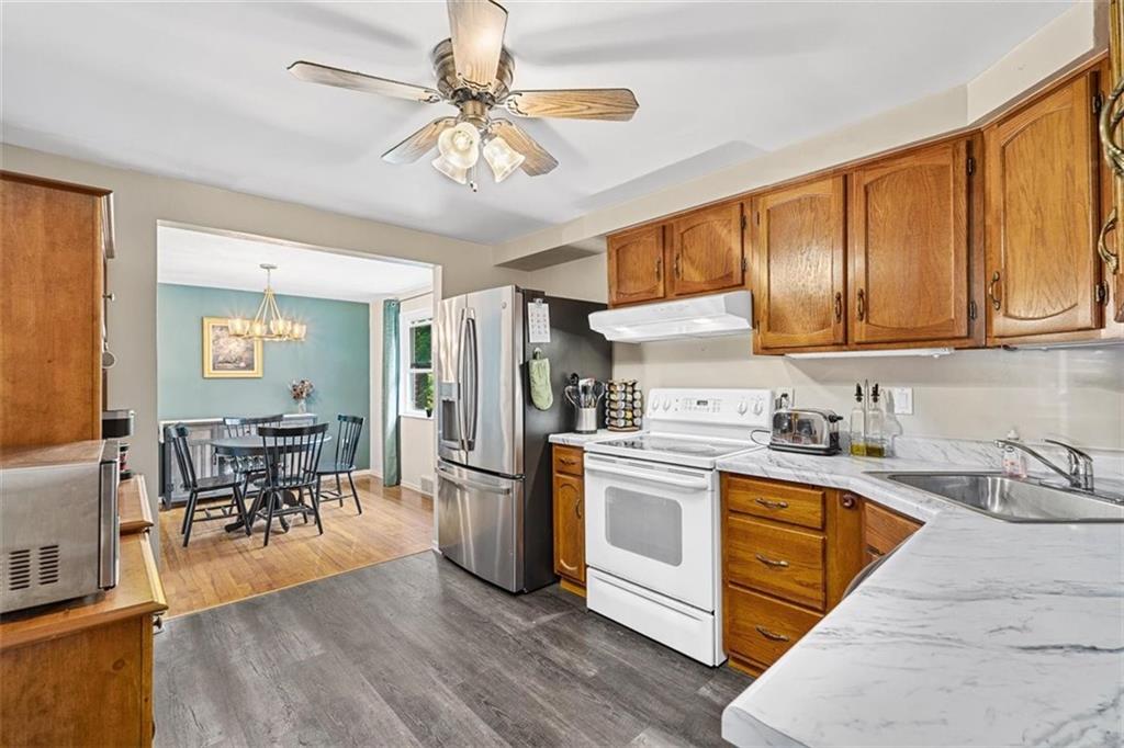 534 Dendron Drive Coraopolis, PA 15108 - Photo 13 of 33 a kitchen with stainless steel appliances granite countertop a stove top oven a sink dishwasher a dining table and chairs with wooden floor
