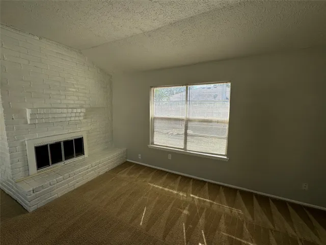 a view of an empty room with a fireplace and a window