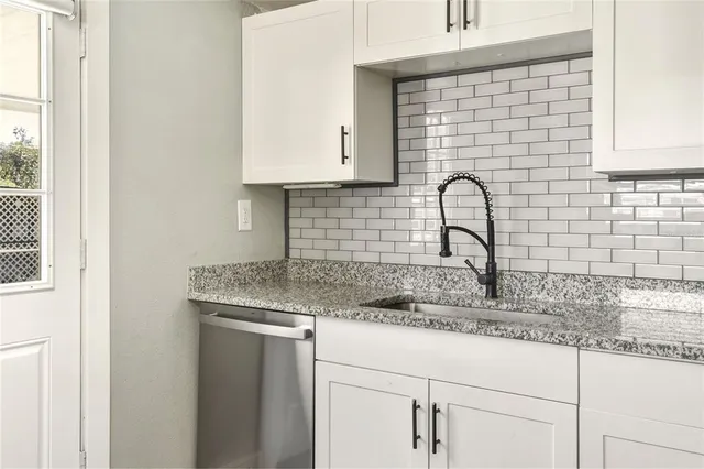 a kitchen with granite countertop white cabinets and a sink