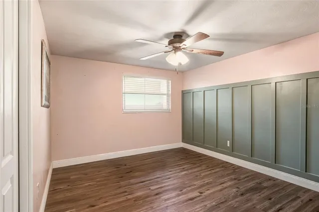 an empty room with wooden floor fan and windows