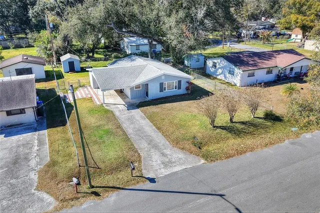an aerial view of a house with swimming pool and large trees