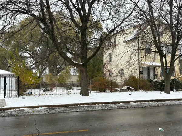 a view of white house with a yard covered with snow