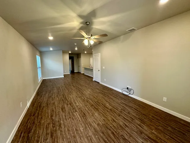 an empty room with wooden floor and a ceiling fan