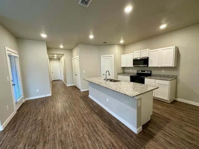 a large kitchen with stainless steel appliances a large counter top a stove a sink dishwasher and a refrigerator