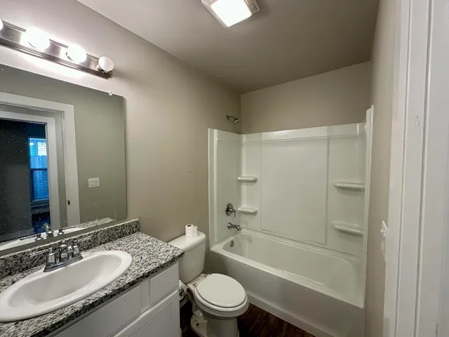a bathroom with a granite countertop sink a toilet and shower