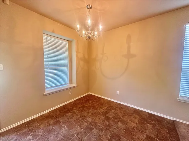 en empty room with windows and chandelier fan
