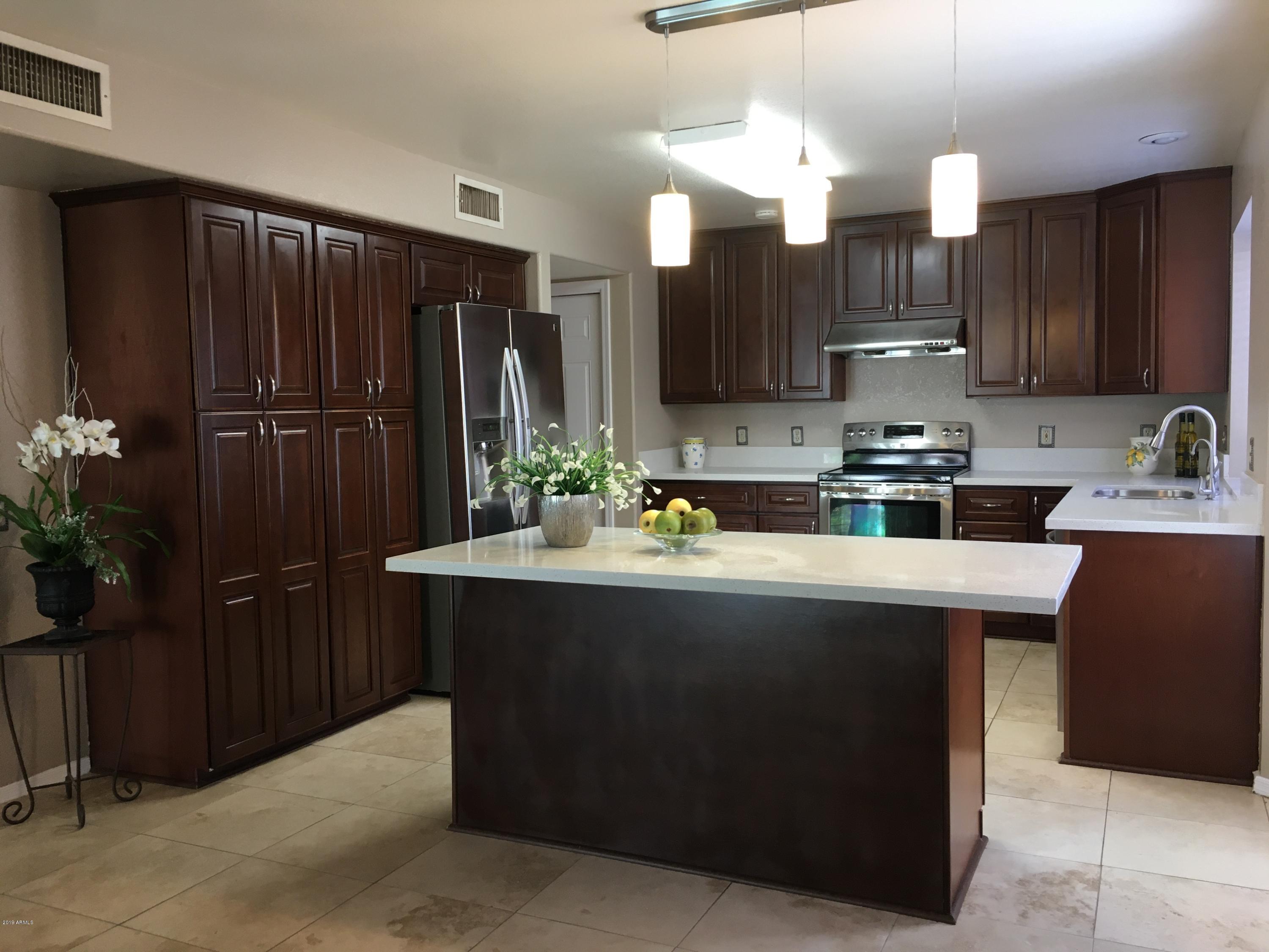 5956 East Phelps Road Scottsdale, AZ 85254 - Photo 1 of 29 a kitchen with stainless steel appliances granite countertop wooden cabinets a refrigerator a stove a oven and a oven with wooden floor