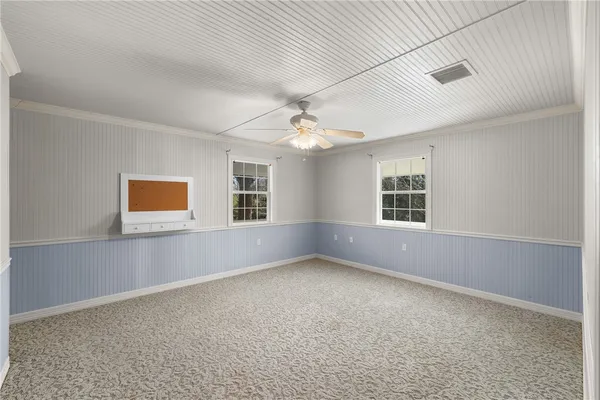 an empty room with windows and chandelier fan
