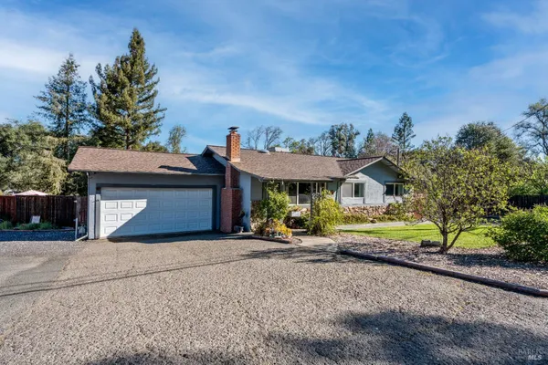 a view of a house with large trees and next to a road