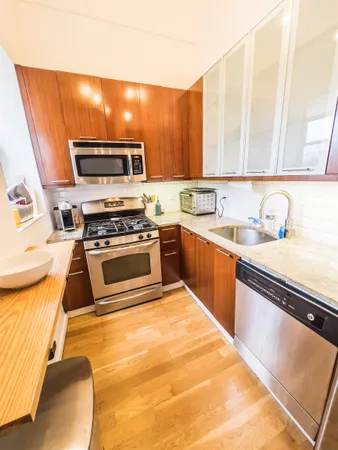 a kitchen with stainless steel appliances a sink a stove a microwave a sink a refrigerator and cabinets